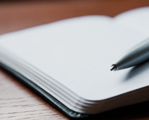 an empty notebook and a pen lie on a table