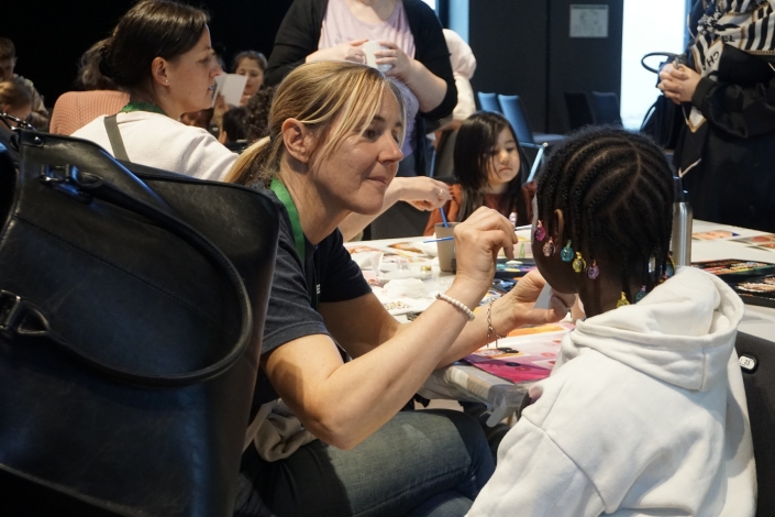 Eine Volunteer schminkt ein Mädchen